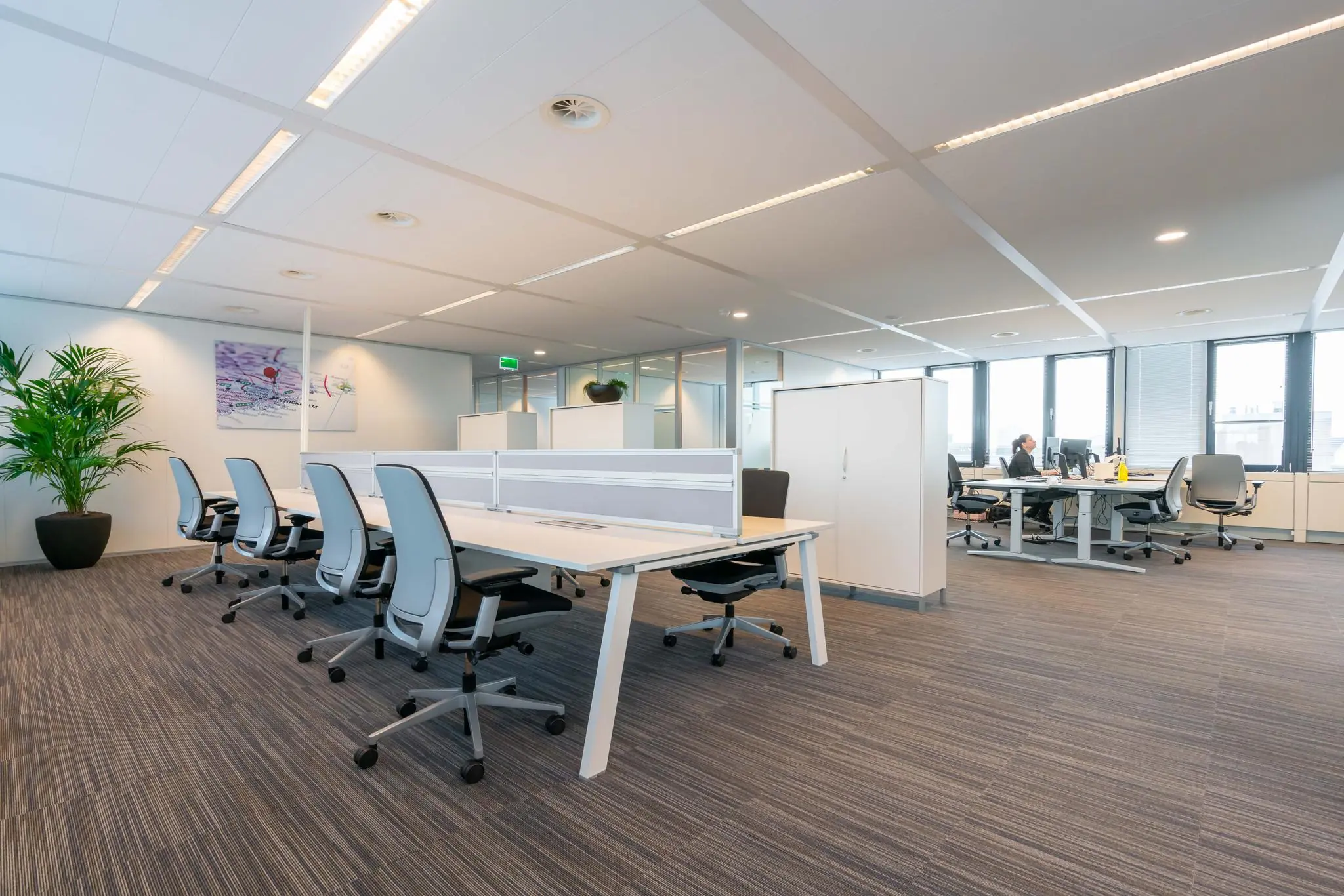 Modern open kantoorinterieur aan de De Bruyn Kopsstraat met bureaus, ergonomische stoelen en grote ramen.